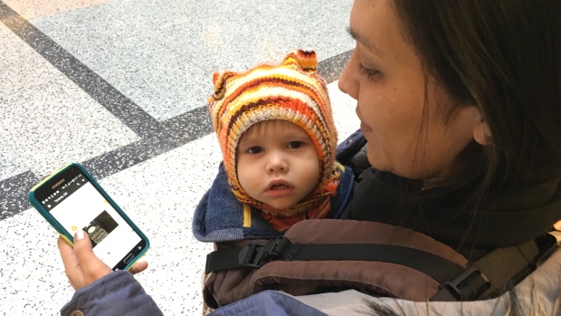 Diane Simon cruises the Bunz app on her phone while holding her son, Aluk.  