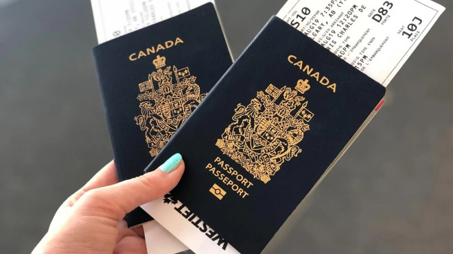 Person holding two Canadian passports with flight boarding passes.