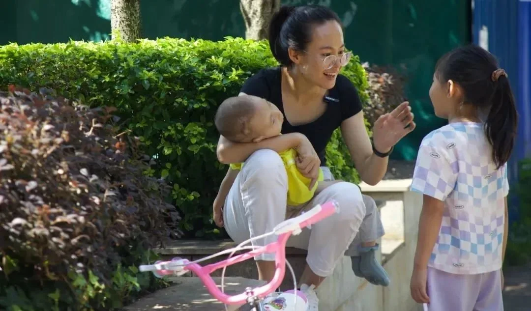 徐伟的妻子带着女儿和儿子在楼下晒太阳